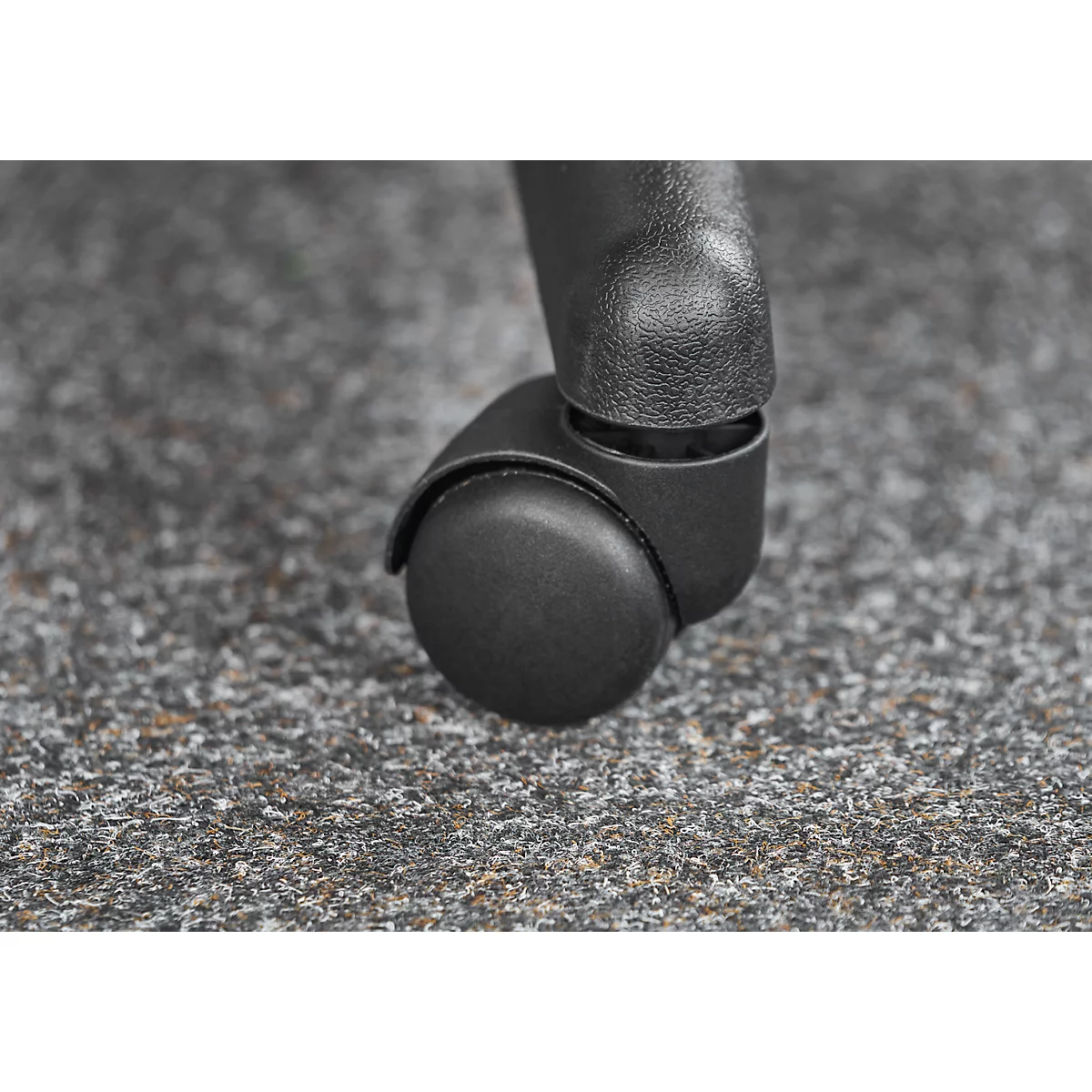 Close-up of a black office chair caster resting on gray carpet.