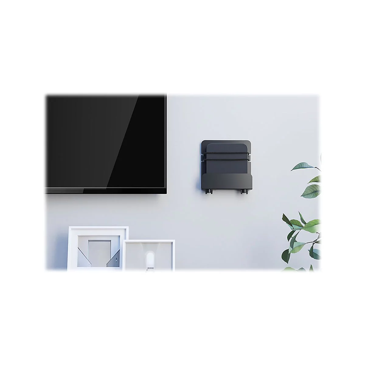 Schwarzes GerÃ¤t an einer Wand, neben Fernseher und Bildern. Eine grÃ¼ne Pflanze steht rechts daneben.