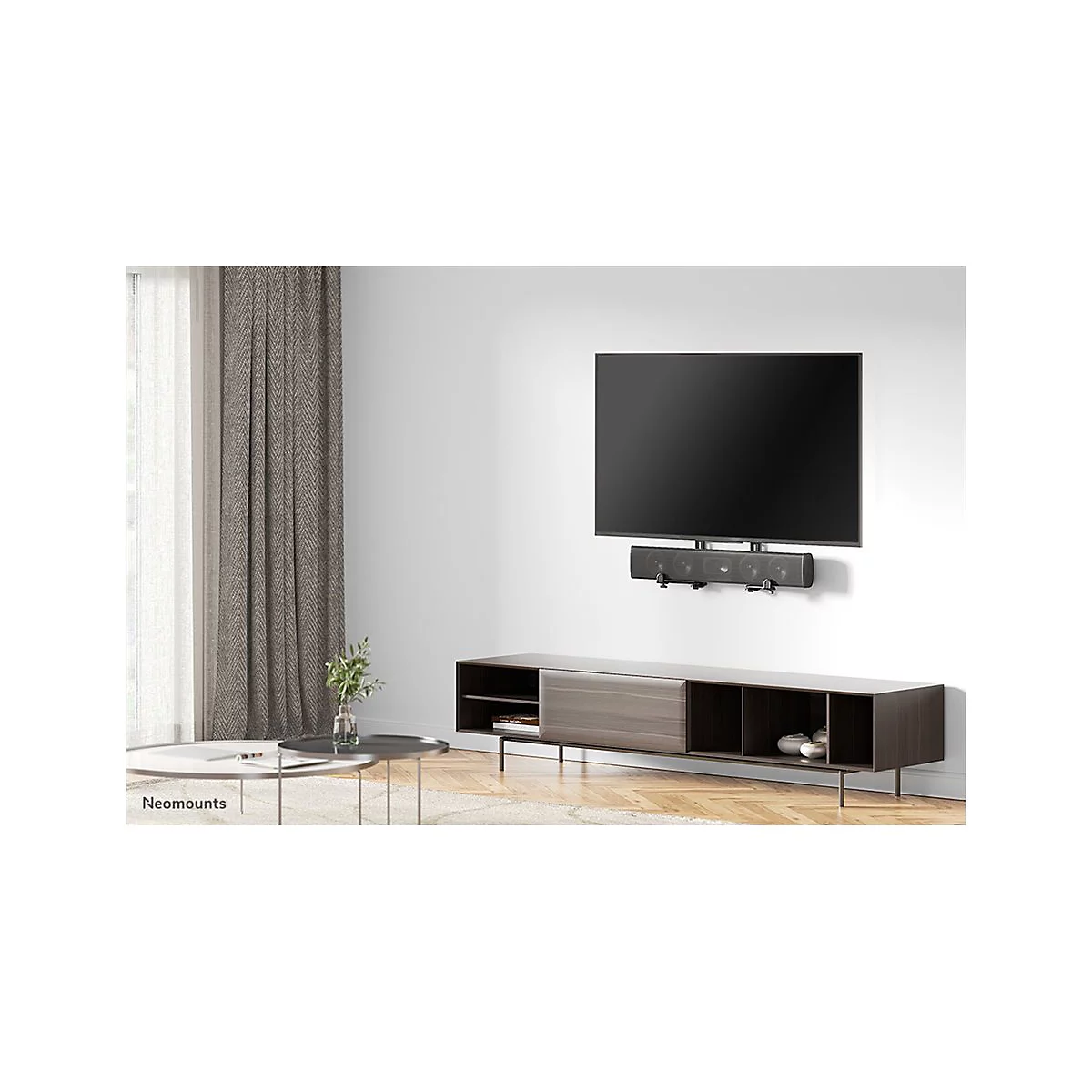 Ein Flachbildfernseher hÃ¤ngt Ã¼ber einer Soundbar und einem Lowboard. Im Hintergrund VorhÃ¤nge und Couchtisch.