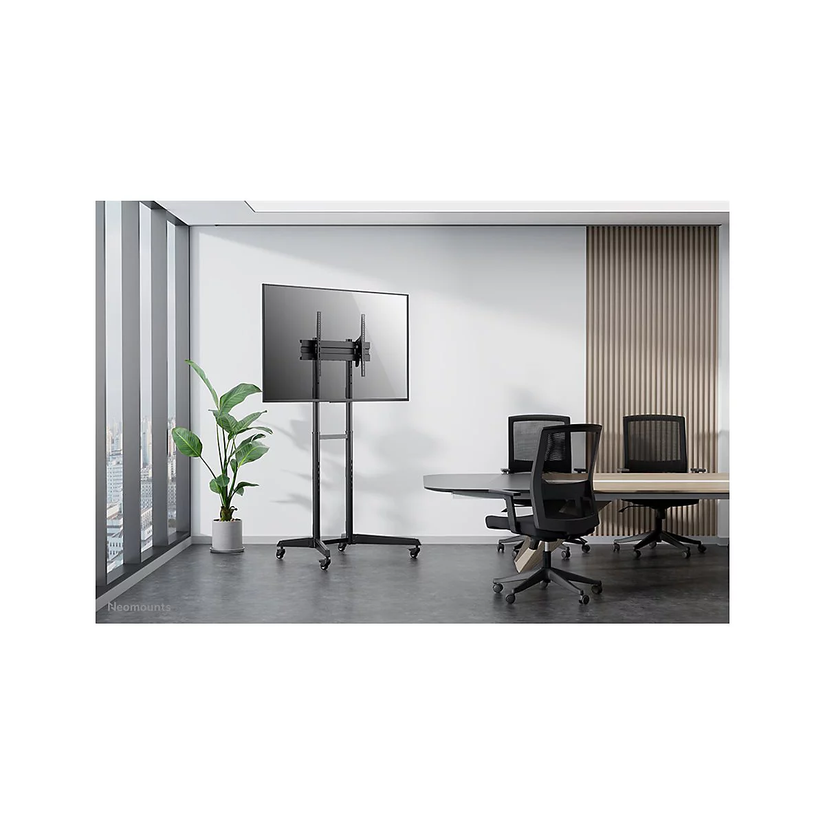 Schwarzer TV-StÃ¤nder mit Bildschirm in einem modernen BÃ¼ro, vor einem Fenster und Tisch.