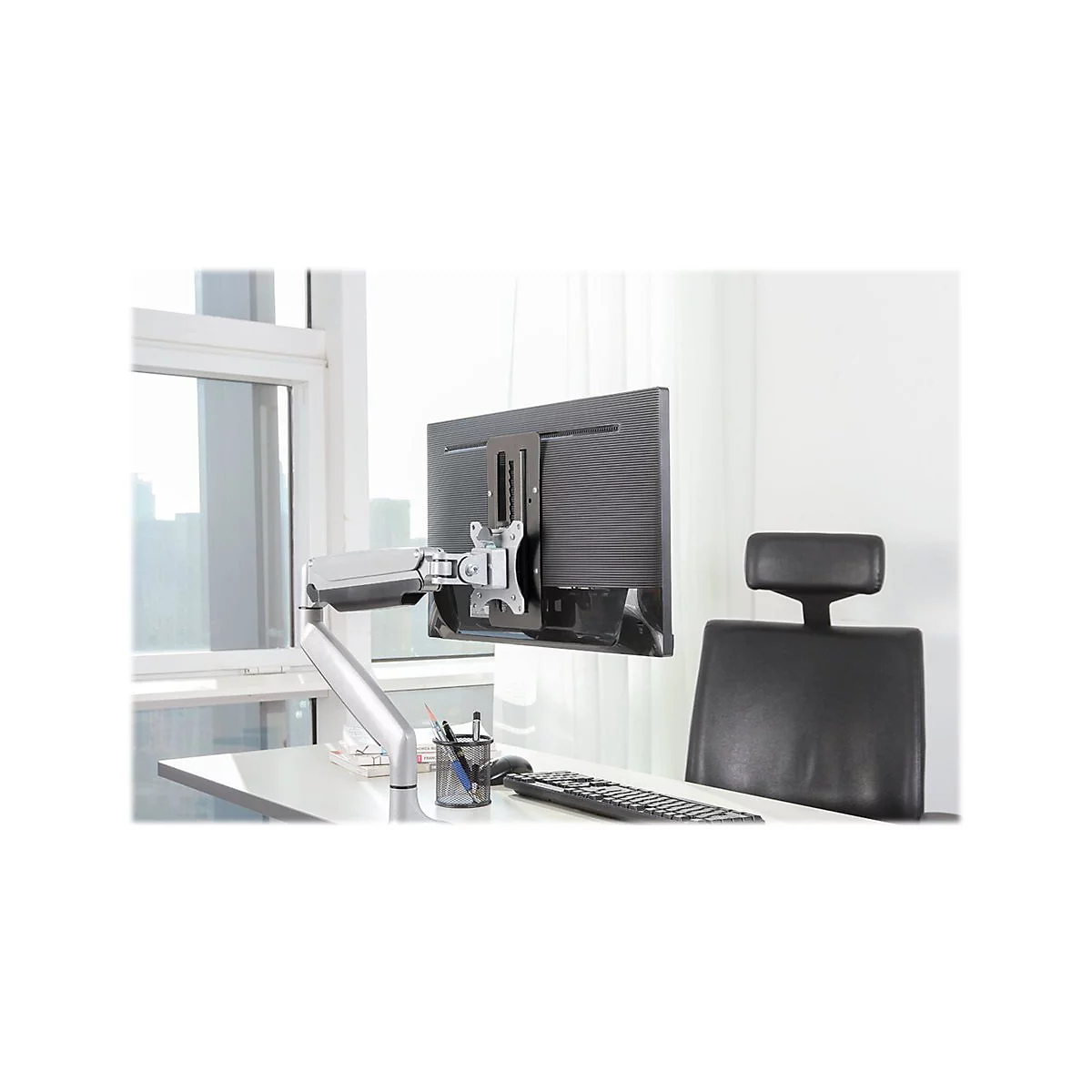 Monitor an Monitorhalterung. Arbeitsplatz mit Tisch, Stuhl, Tastatur und Stifthalter.