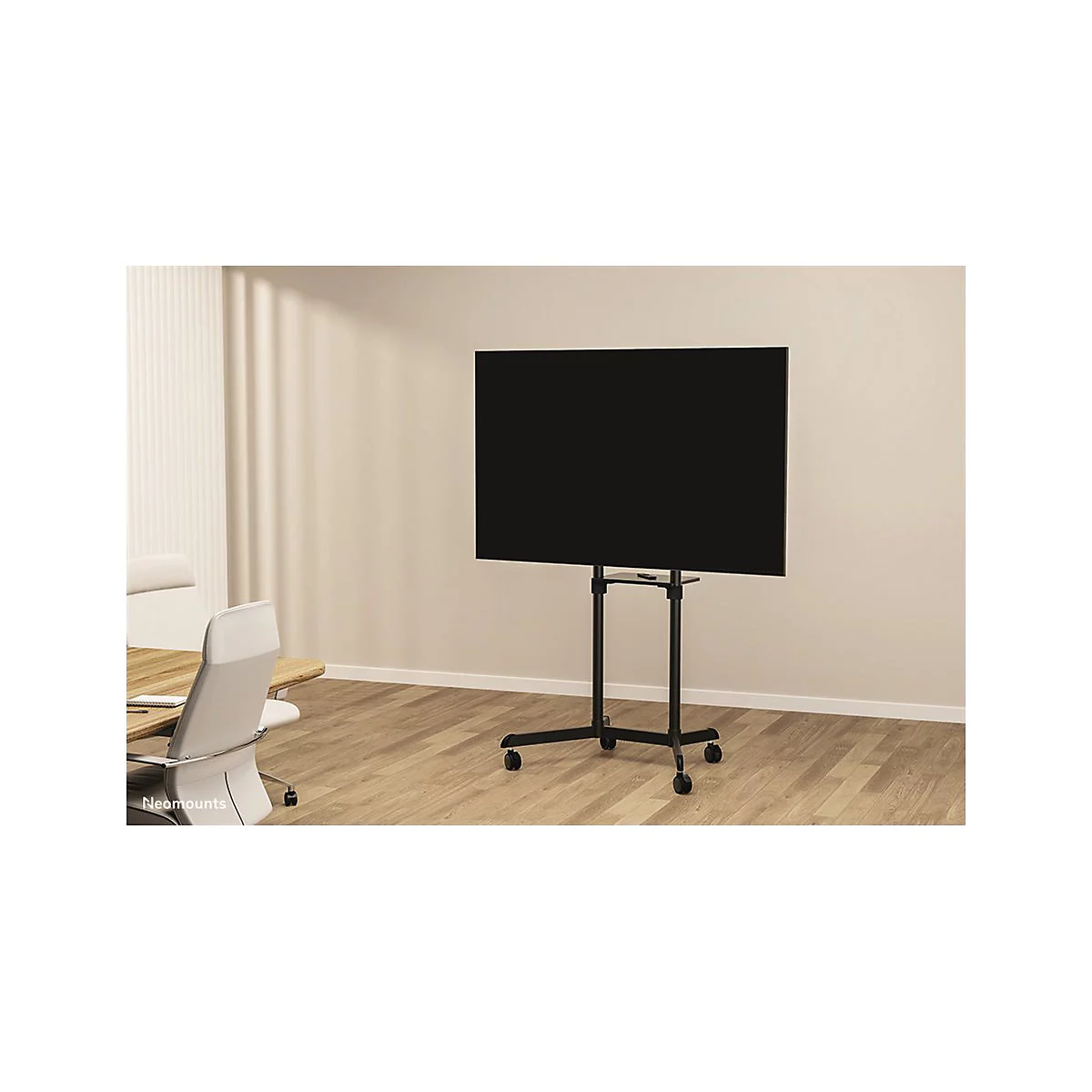 Téléviseur à écran plat noir sur un support noir à roulettes. Aménagement de bureau en arrière-plan.