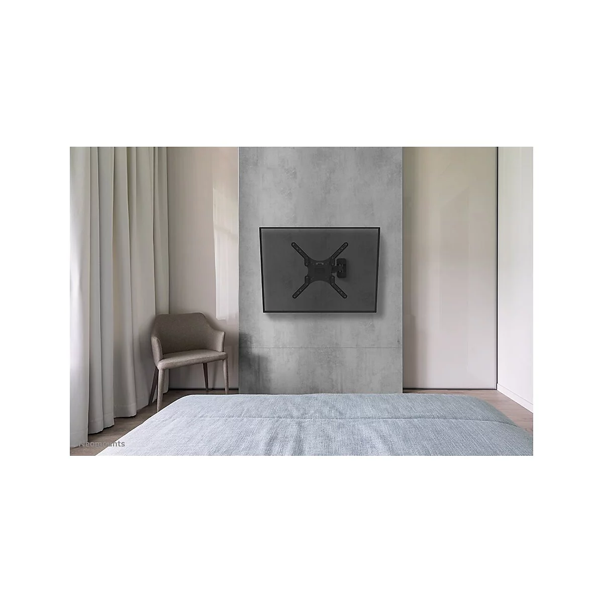 Ein schwarzer TV-Wandhalter hängt an einer grauen Betonwand in einem Schlafzimmer. Ein Bett und Stuhl sind ebenfalls zu sehen.