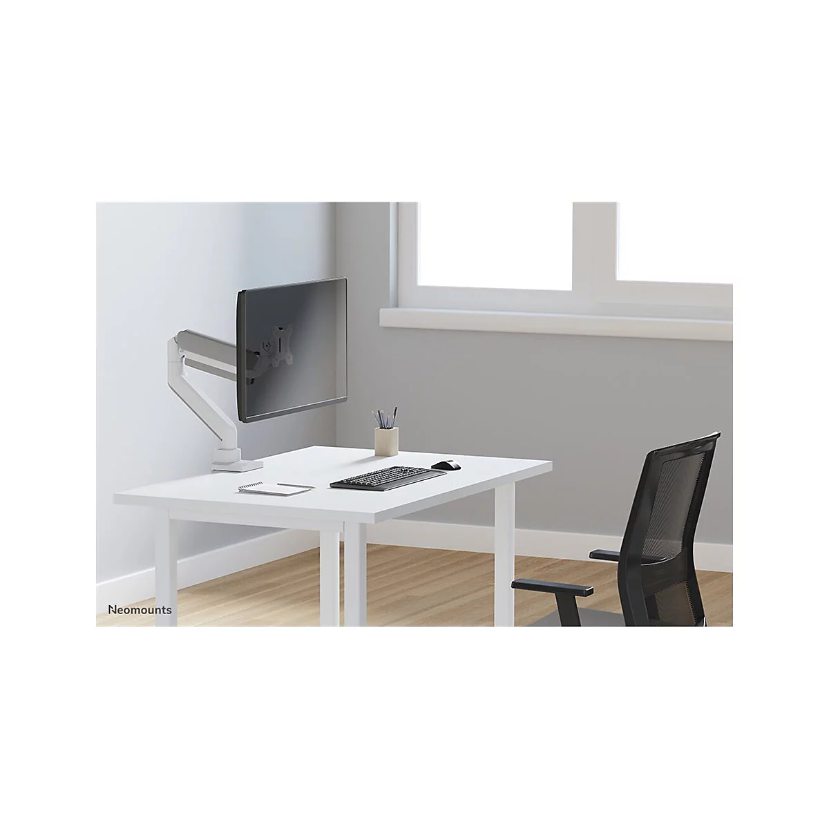Schreibtisch mit Monitorhalterung. Auf dem Tisch liegen Tastatur, Maus und Notizblock. Im Hintergrund ein Fenster und ein Bürostuhl.