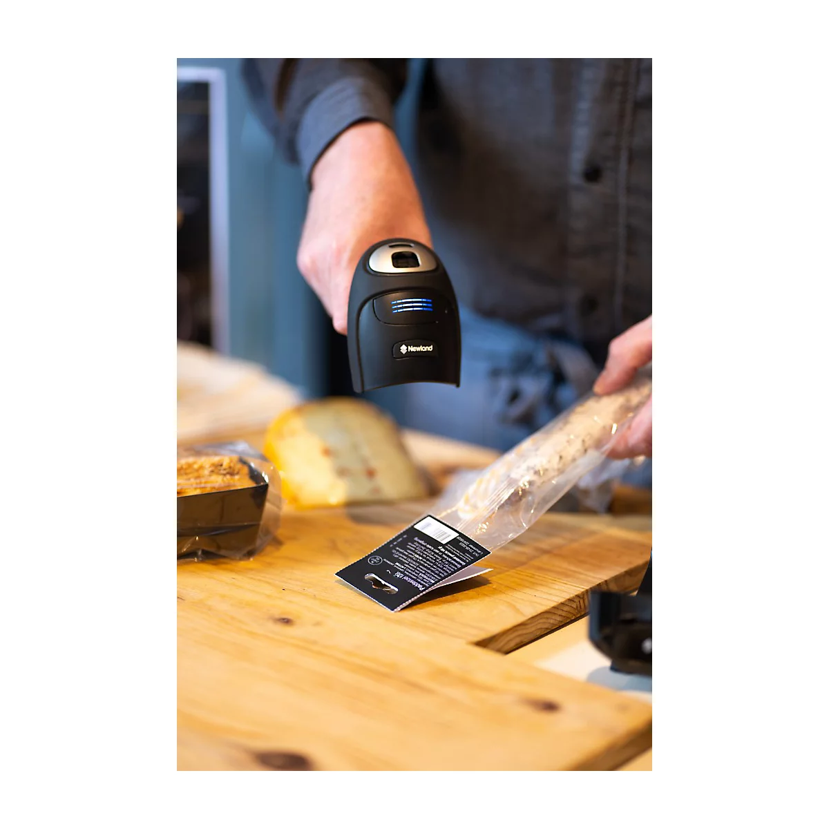 Eine Frau im blauen Overall sitzt in einem Gabelstapler. Sie hält ein Gerät in der Hand und schaut lächelnd nach oben. Im Hintergrund sind Lagerregale.
