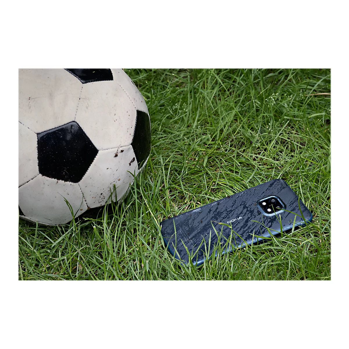 Ein Smartphone und ein FuÃŸball liegen im Gras.