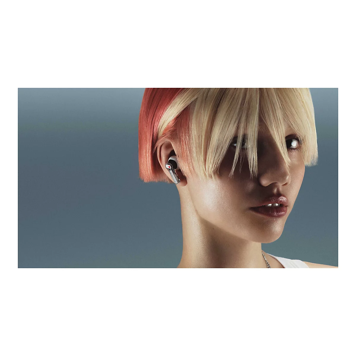 Person mit blond-roten Haaren trägt einen modernen In-Ear-Kopfhörer im Ohr.