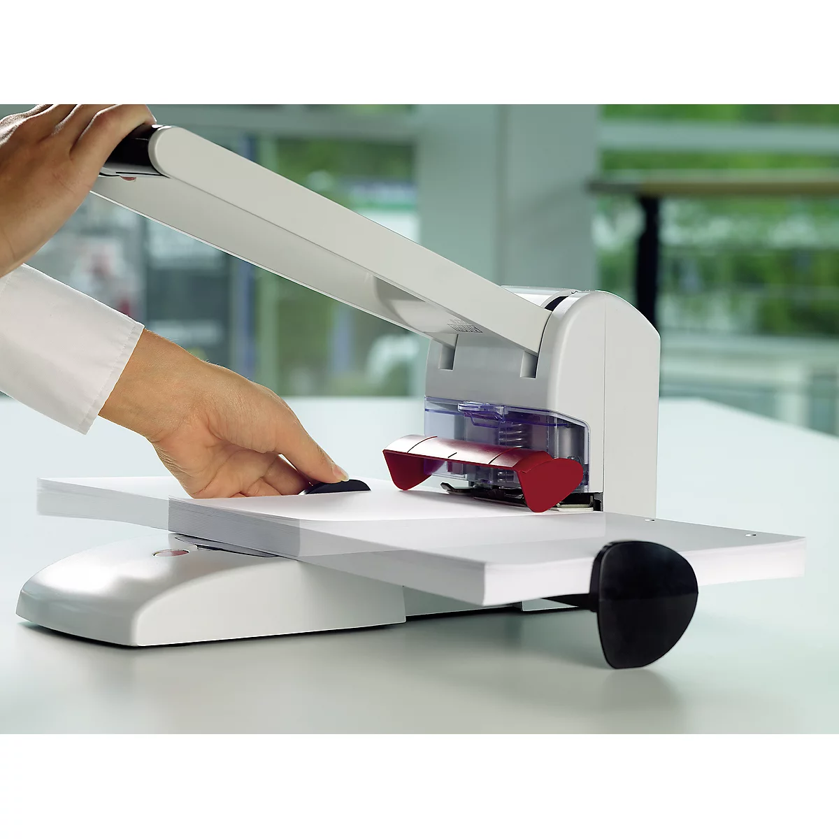 Person using a white paper punch. Red part of the punch is visible.