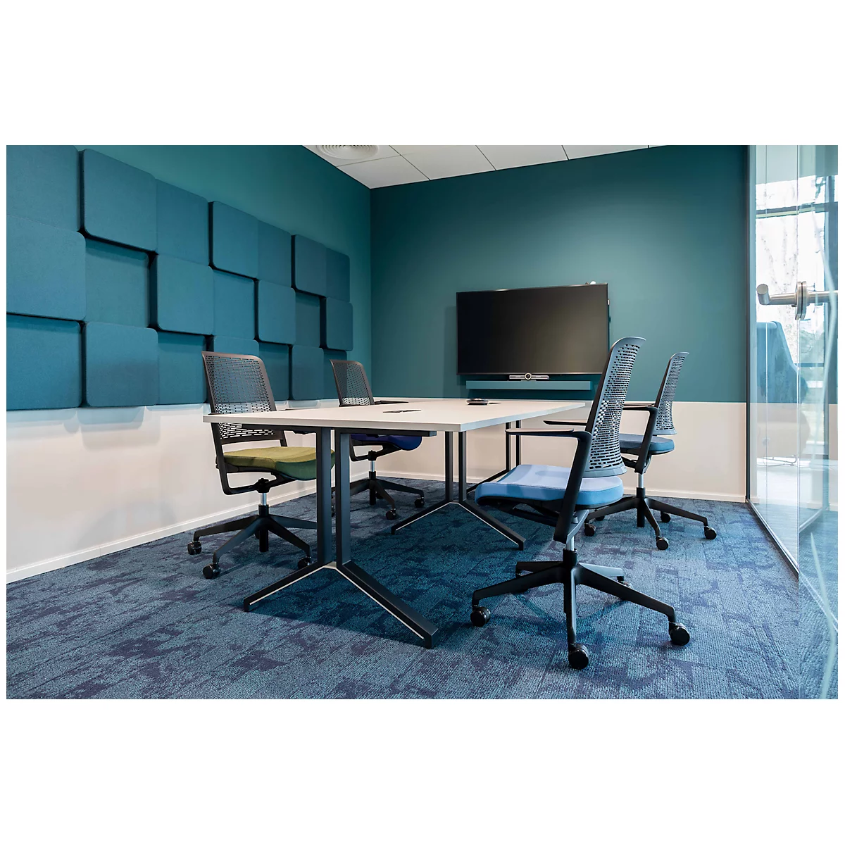 Vergaderzaal met tafel, stoelen en scherm. Blauwe wandbekleding, blauw tapijt.