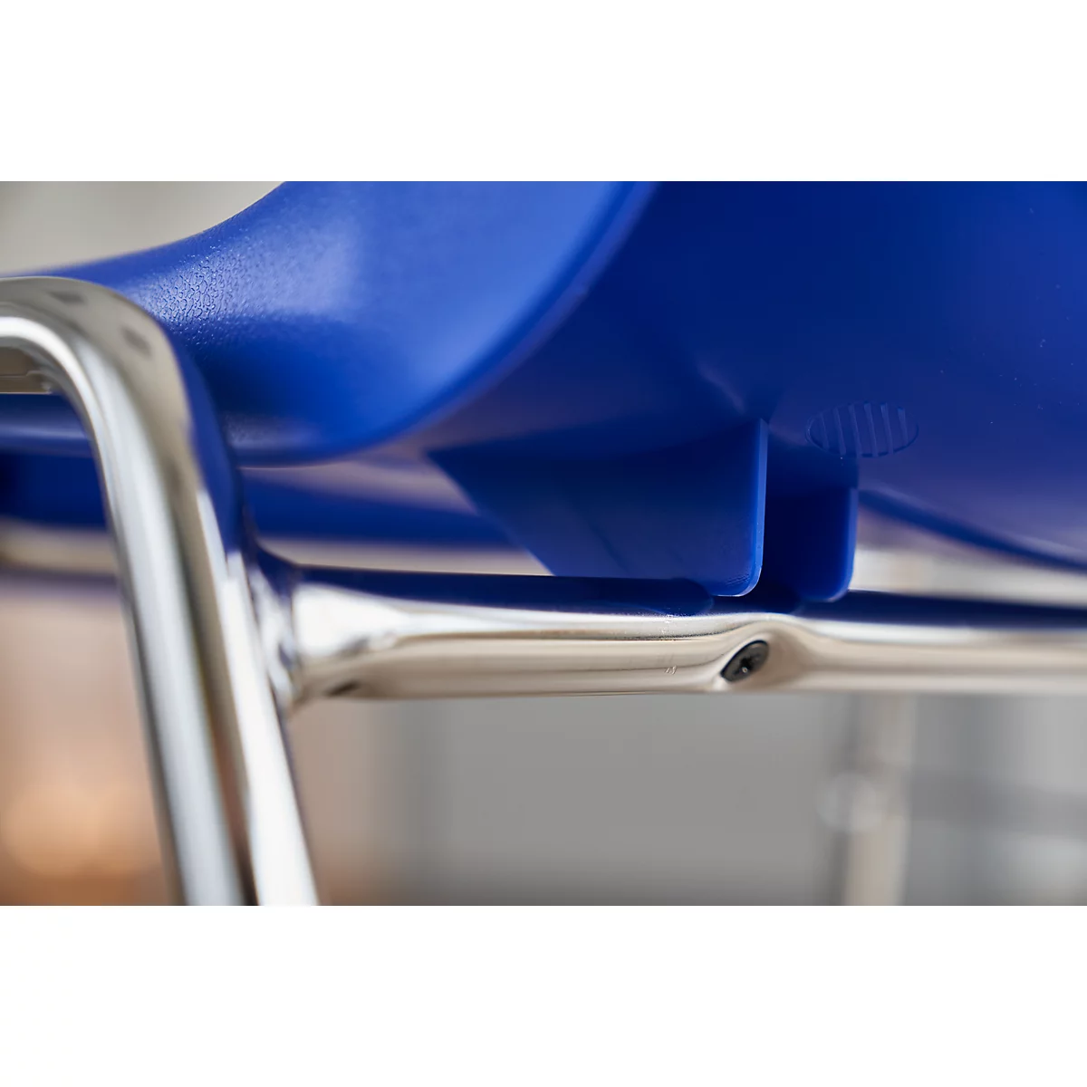 Detailaufnahme eines blauen Stuhls mit Chromgestell.