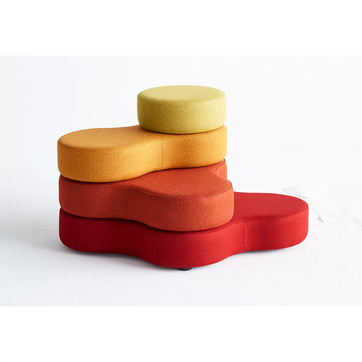 Gestapelte, bunte Sitzhocker: Rot, orange, gelb. Der obere Hocker ist rund.