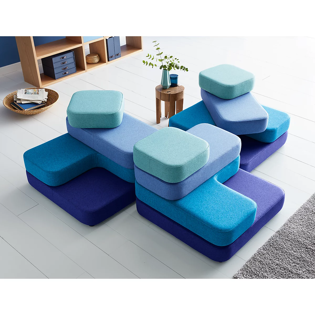 Modulares Sofa in verschiedenen Blautönen, quadratische Kissen auf den Elementen.
