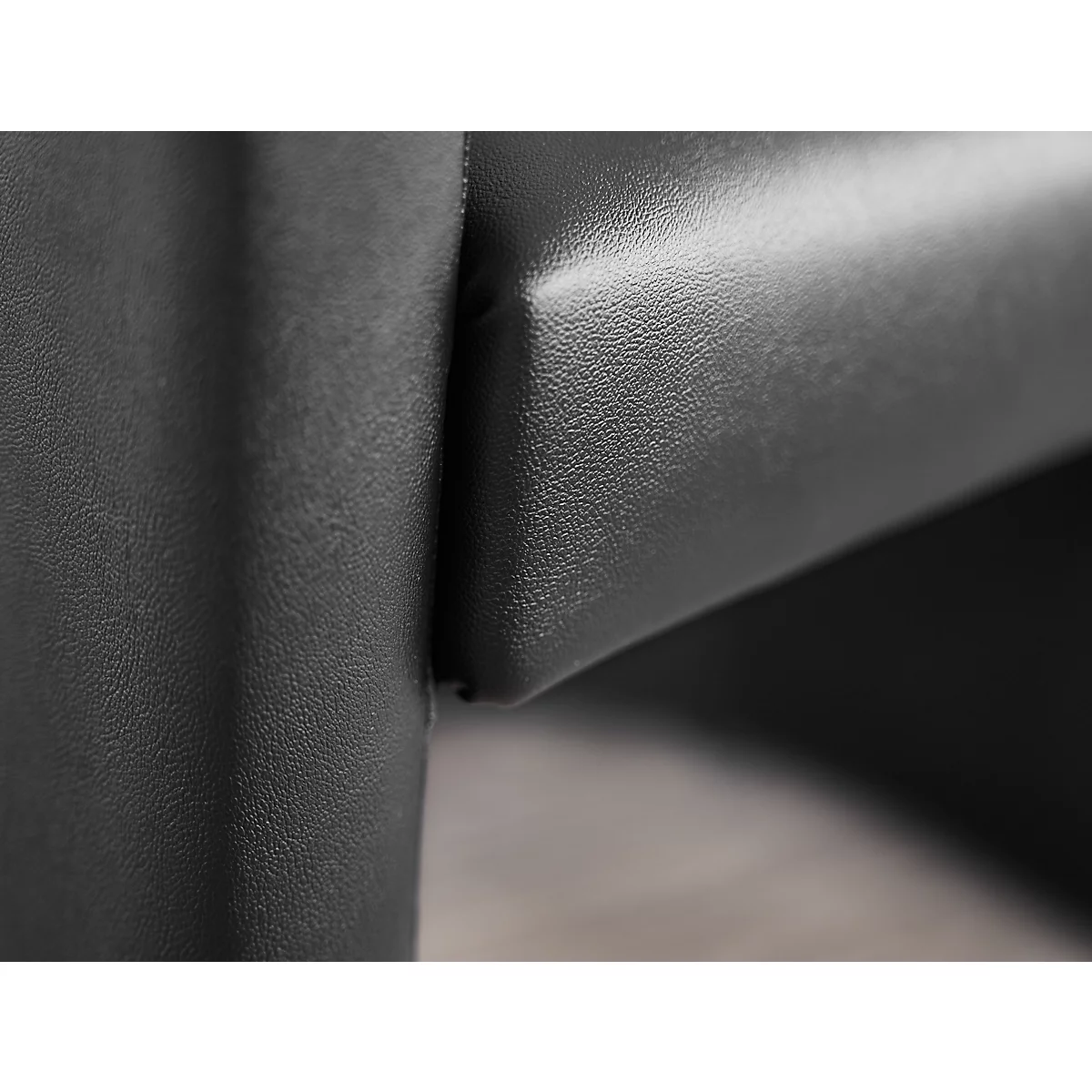 Nahaufnahme eines schwarzen Ledersofas, Details der Naht. Holzfussboden im Hintergrund.