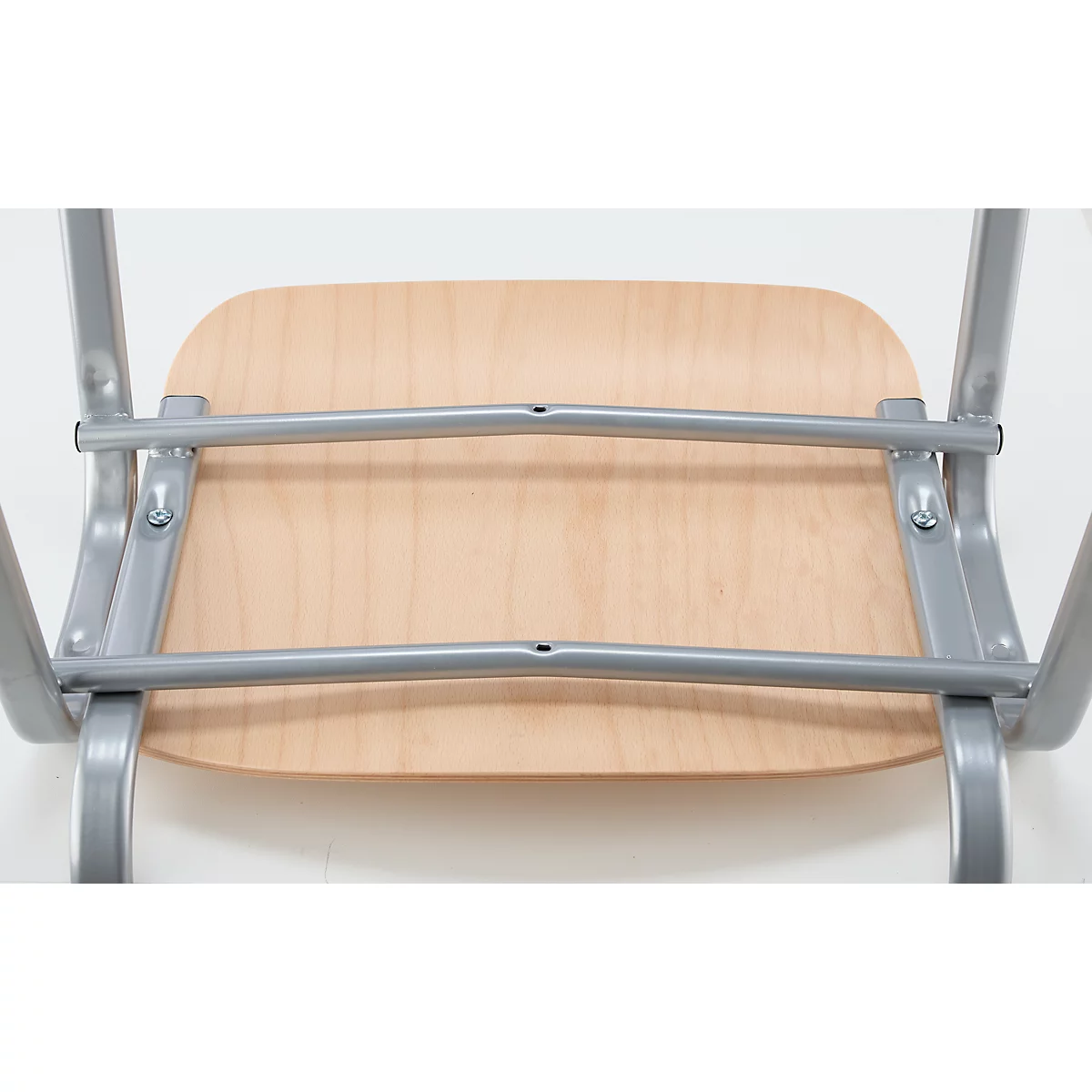 Underside view of a chair. Wooden seat, silver metal legs and crossbars.