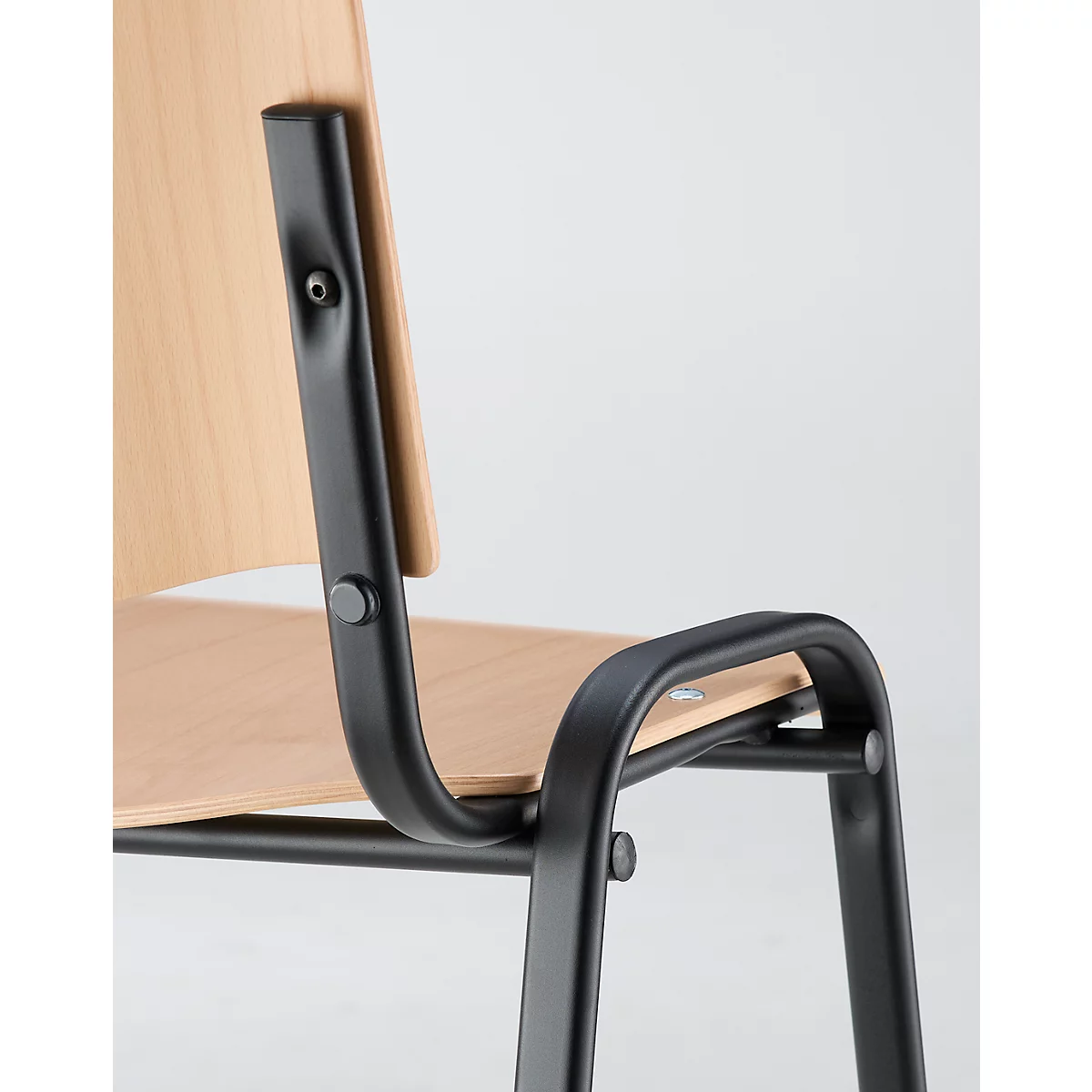 Close-up of a chair with light brown seat and backrest. Black metal frame, details like screws visible.