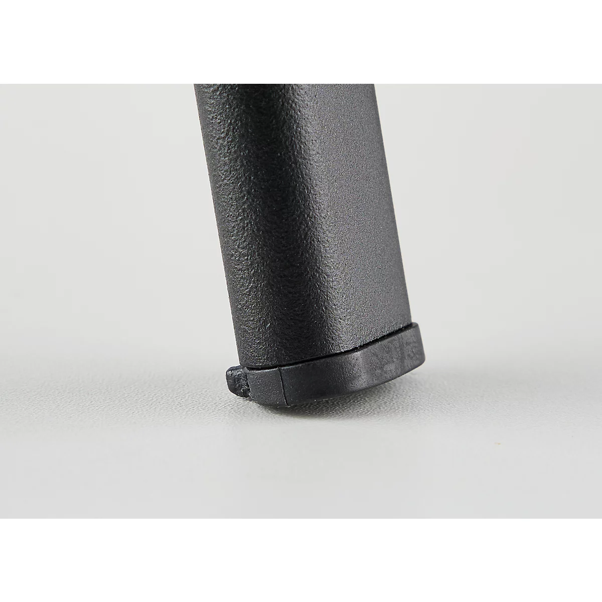 Close-up of the lower part of a black magazine with a ridged texture resting on a white surface.