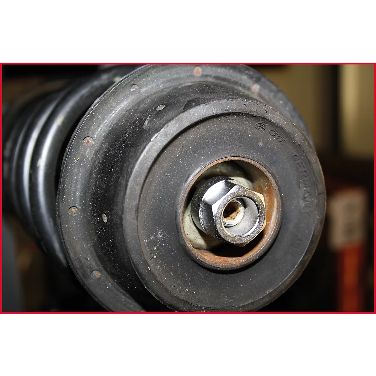 Nahaufnahme eines Stoßdämpfers mit Schraube, Unterlegscheibe und Feder. Schwarze Gummiteile.