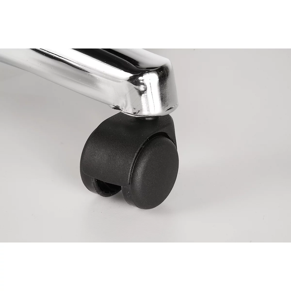 Close-up of a desk chair wheel. The black wheel is attached under a chrome metal foot.