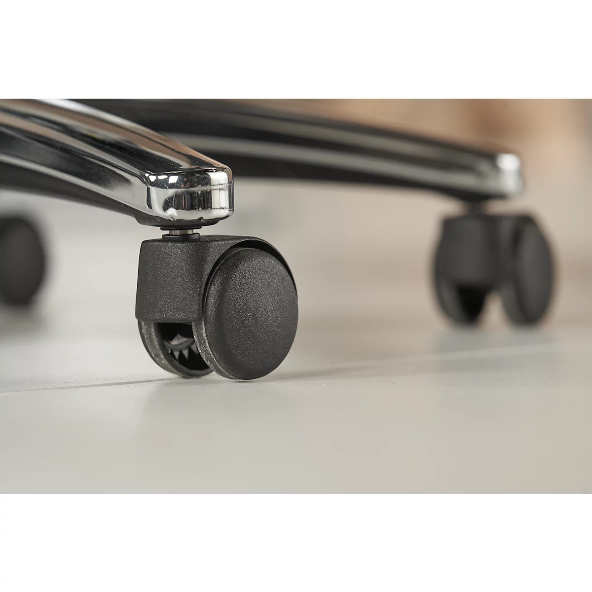 Close-up of the wheels of an office chair. Black wheels stand on a white surface.