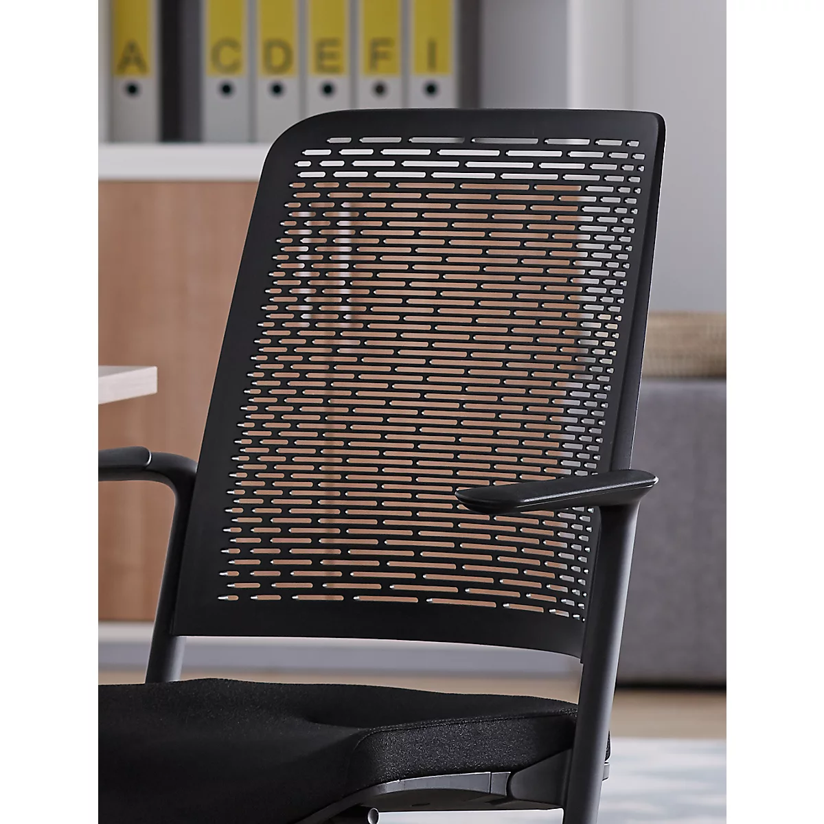 Black office chair with perforated backrest. Folders are visible behind.