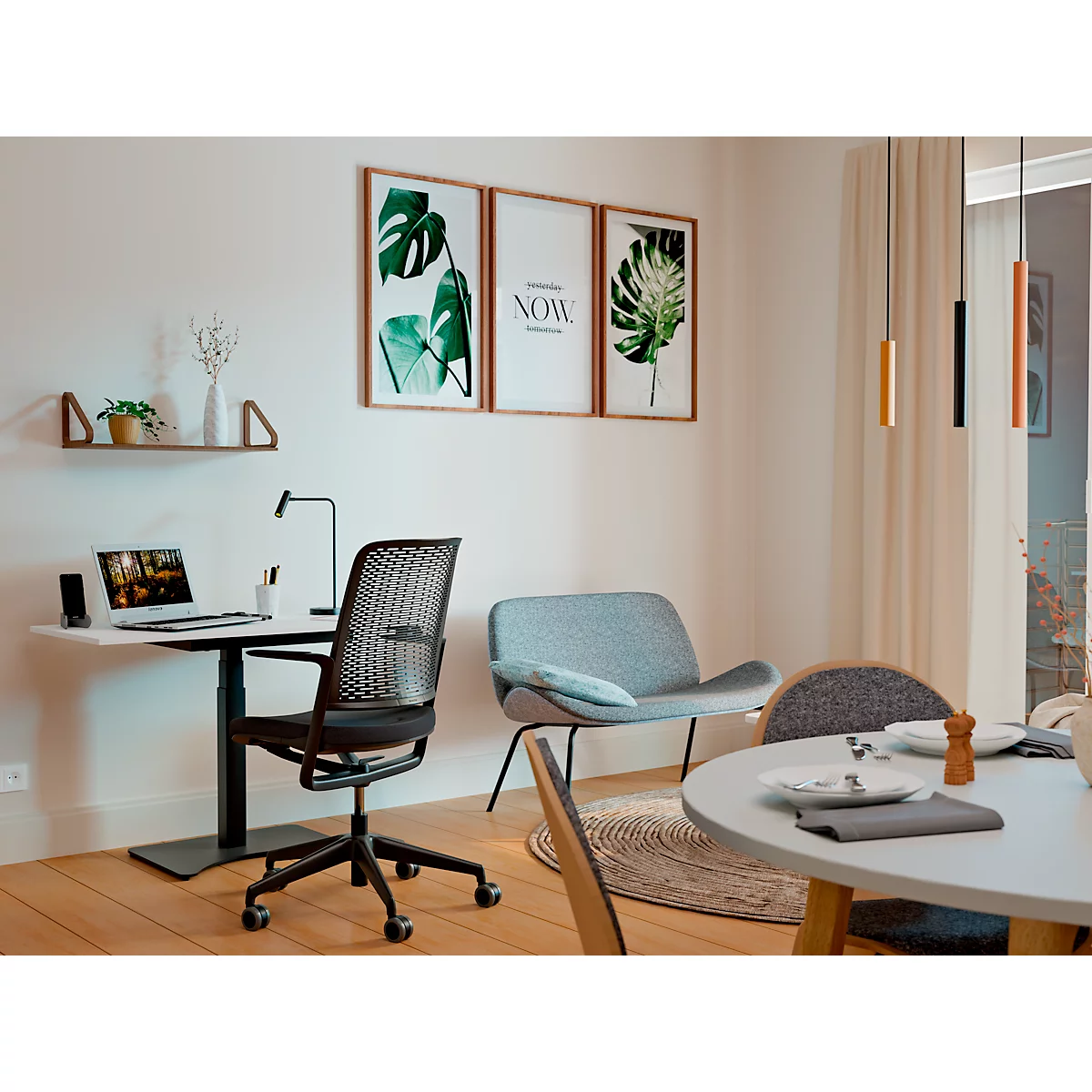 A modern dining room with a desk, a chair, and a sofa. Pictures hang on the wall. There is also a pendant light.