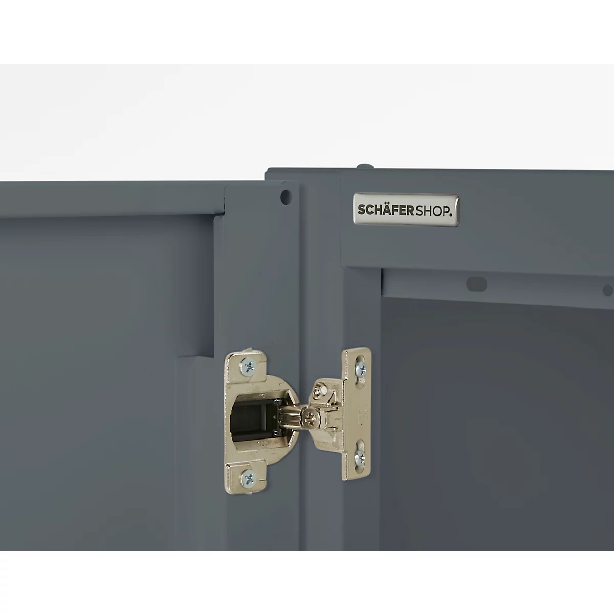 Close-up of a grey cabinet with a silver hinge attachment. The text 'SCHÄFERSHOP' can be seen.