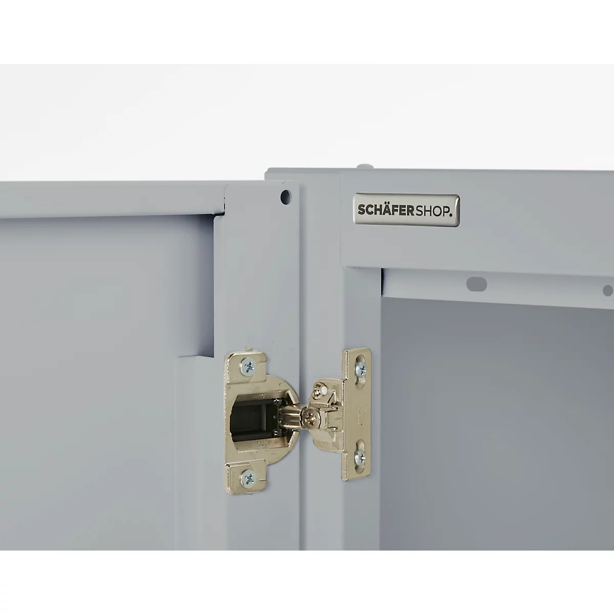 Close-up of a cabinet door with hinge. Gray door with "SCHÄFERSHOP" logo. Shiny metal hinge on gray case.