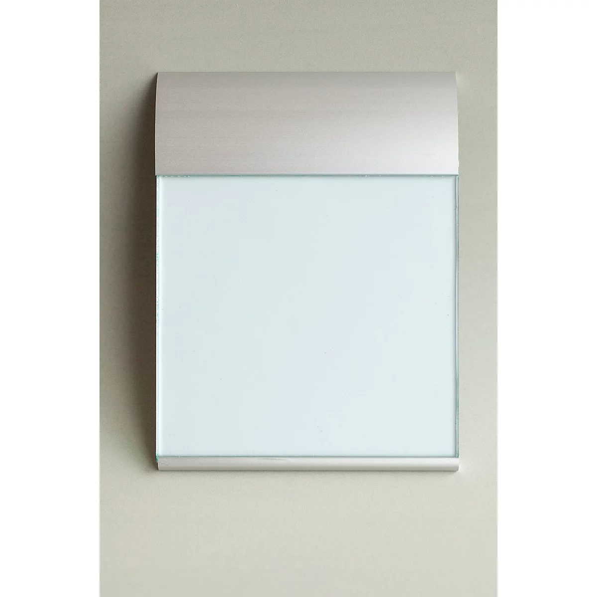 Rectangular, white board with silver frame and cover, on light gray wall. Slightly arched at the top.