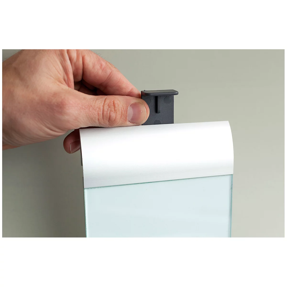 A hand attaches a gray holder to a white case. A glass panel is visible behind it.