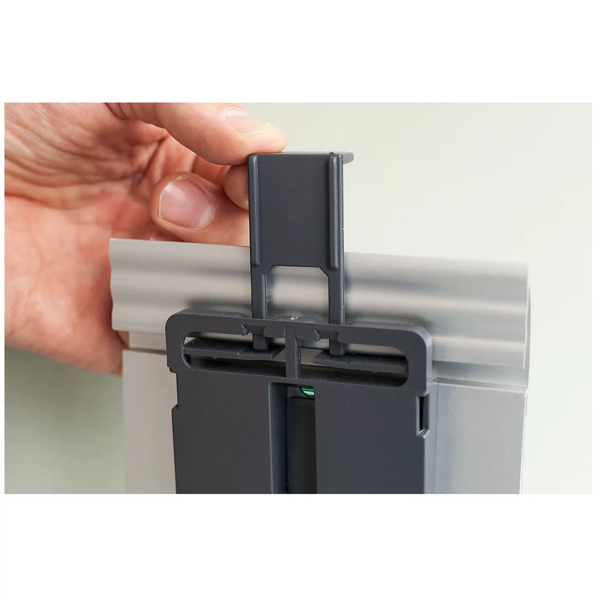 Person holding grey plastic part over a silver rail. The part is being inserted.