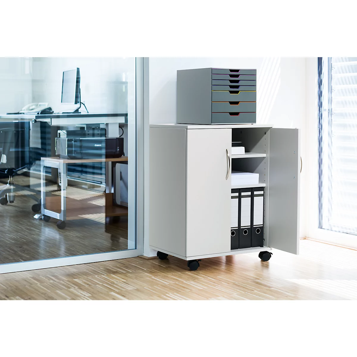 Grey office cabinet on wheels with open doors, folders and drawers.