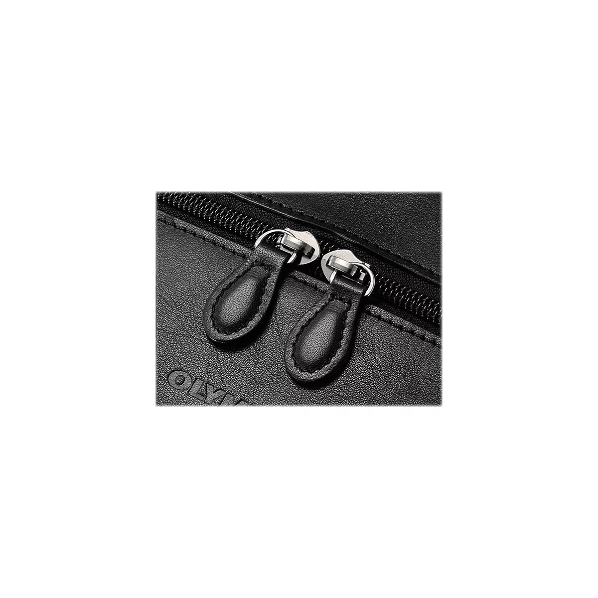 Gros plan sur deux tirettes de fermeture éclair en cuir noir et une fermeture éclair argentée sur du cuir noir.