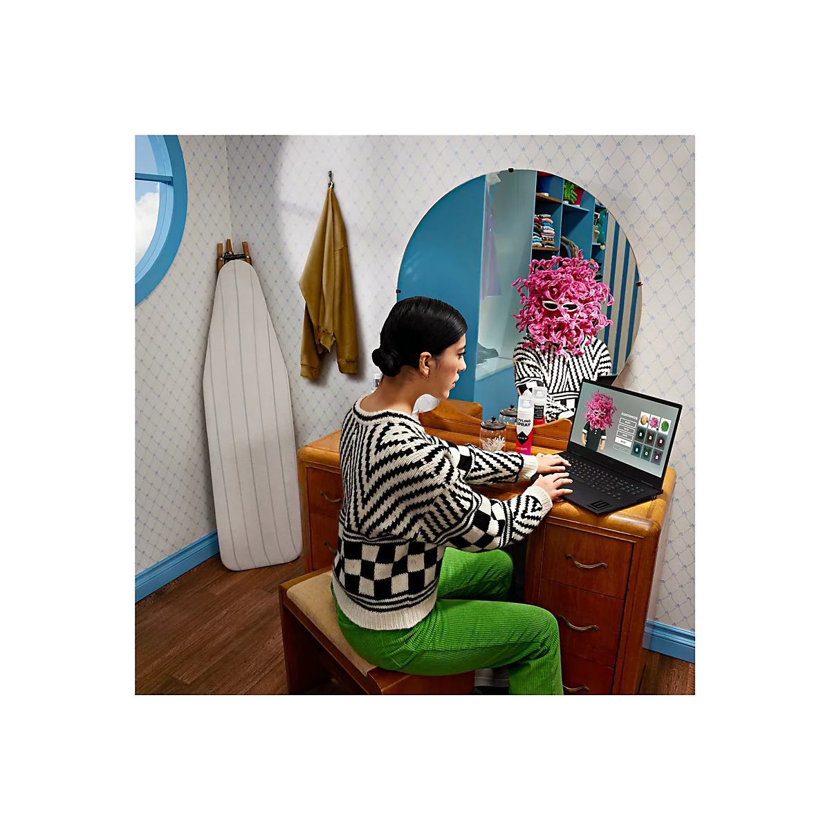 Frau am Laptop, Spiegelbild mit pinkfarbener Perücke, dekoriertem Raum, Spiegel, Bügeleisen.