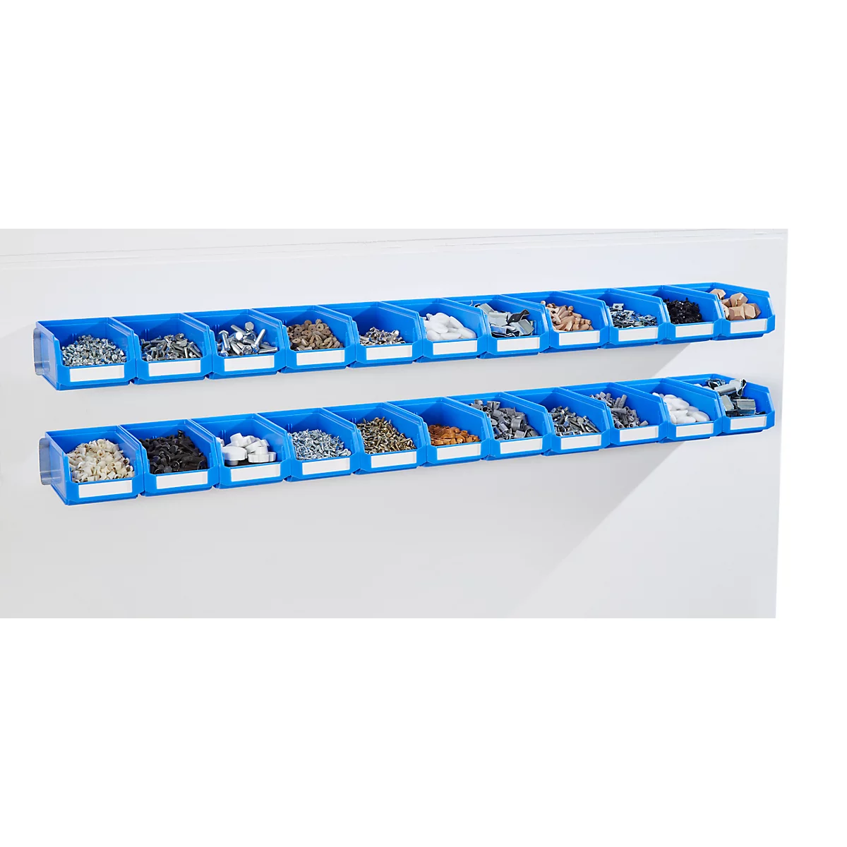 Twee rijen blauwe wandboxen met diverse kleine onderdelen, aan een witte muur. De dozen zijn voorzien van labels.