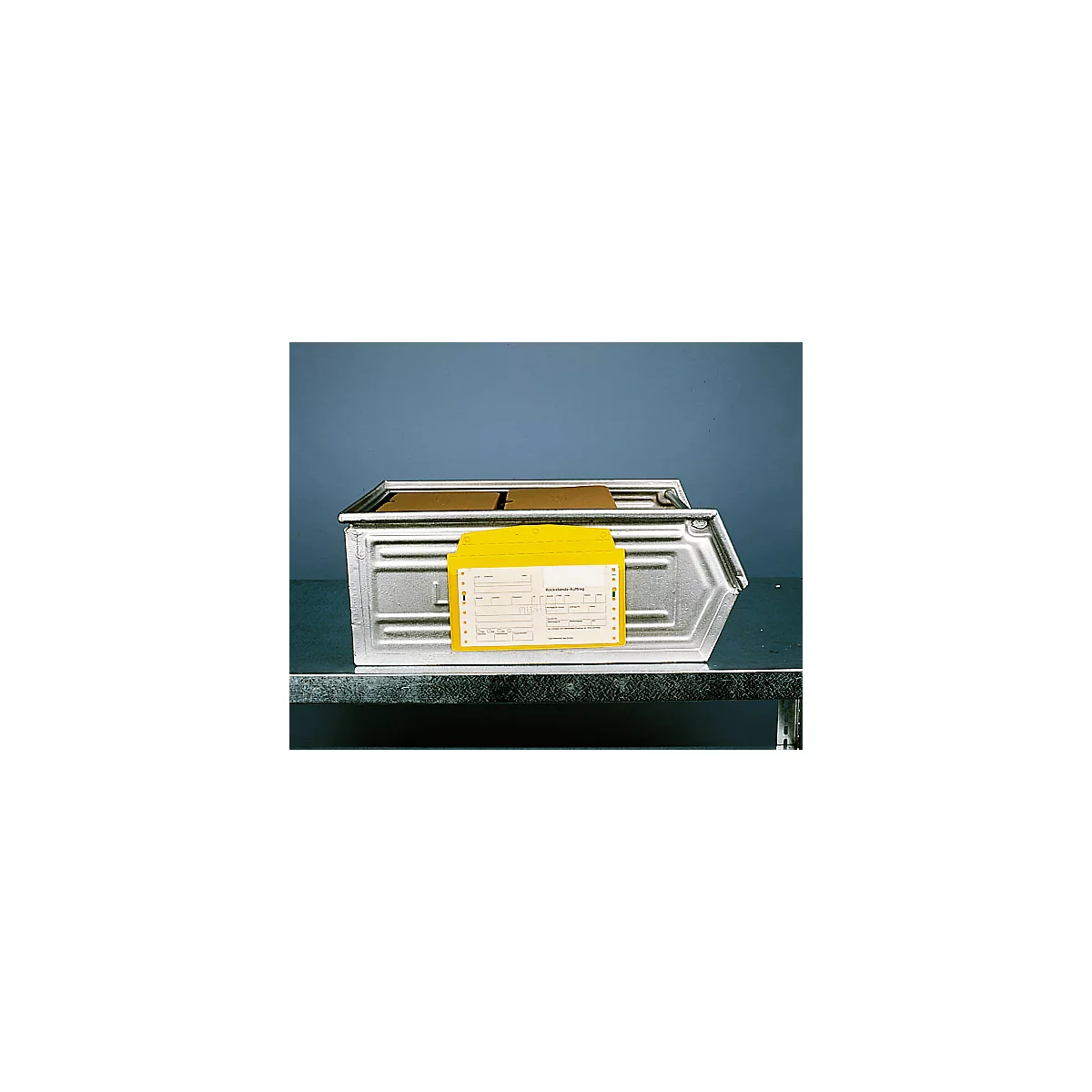 Metal box with yellow documents. Partially legible inscription. Box on table, blue background.