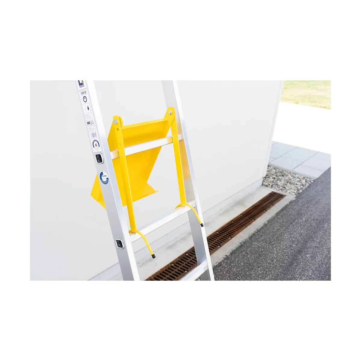 Échelle argentée avec accessoire jaune devant un mur blanc. Plan détaillé.