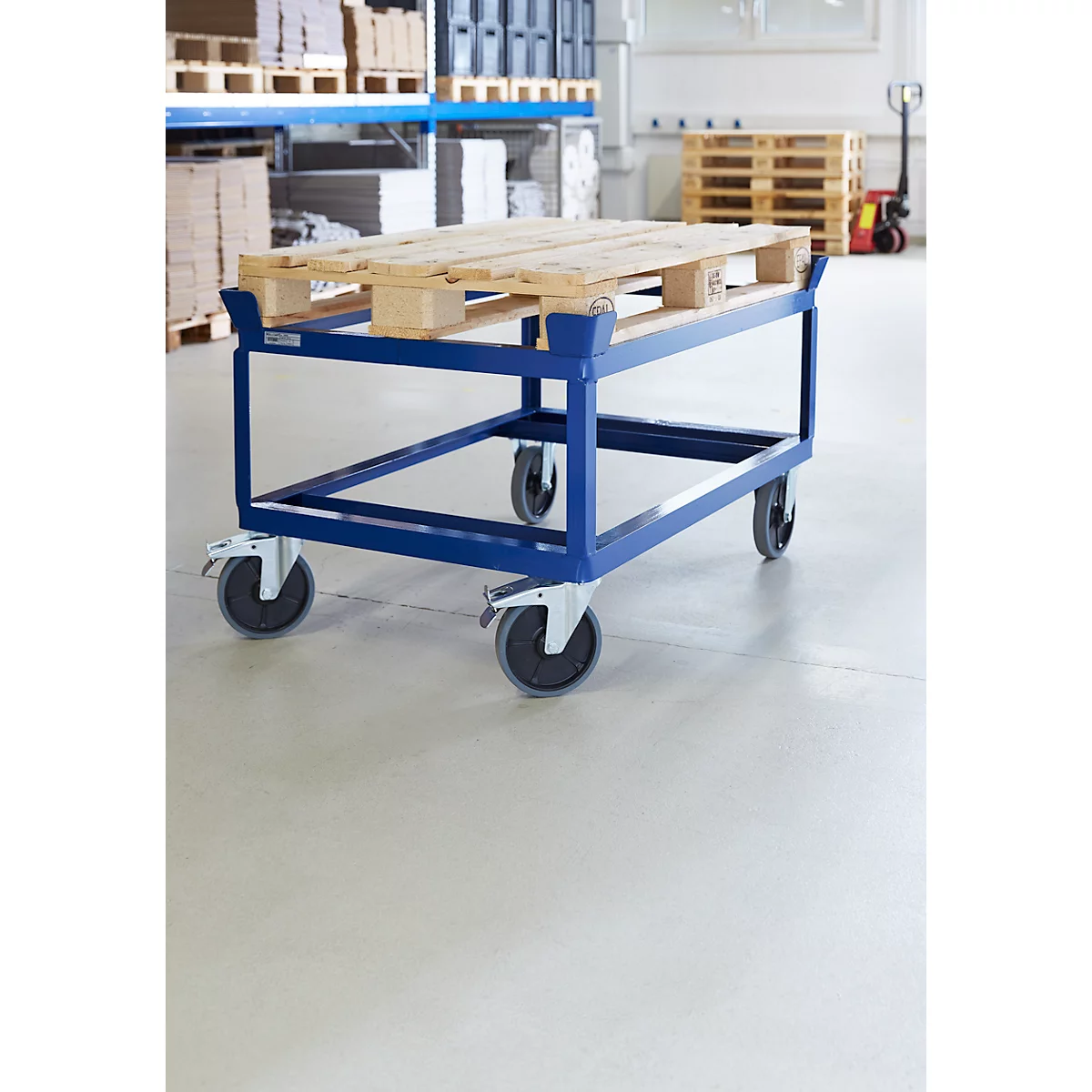 A blue transport cart with a pallet in a warehouse. The cart has four wheels.