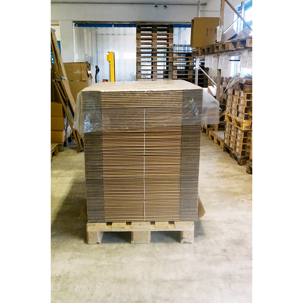 A stack of new, unused cardboard boxes on a pallet in a warehouse.