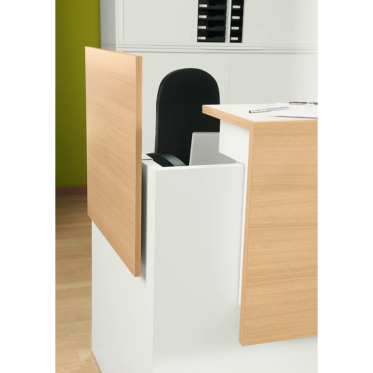 Un bureau avec des surfaces en bois et une base blanche, une chaise noire et un mur vert en arrière-plan.