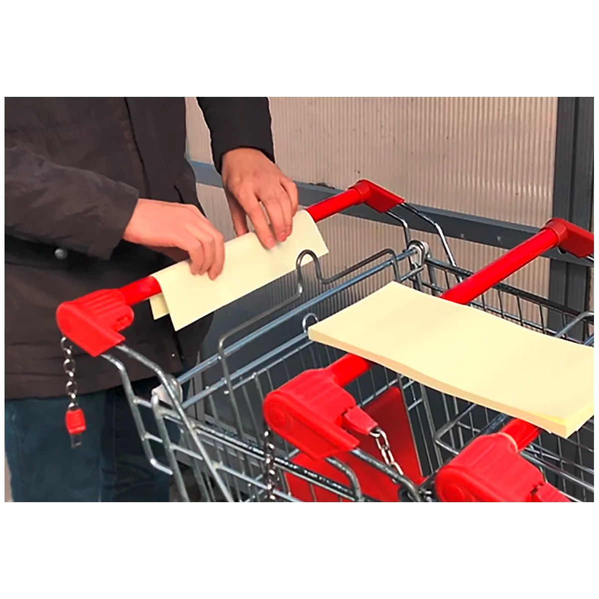 Personne plaçant du papier sur un chariot. Poignées rouges, papier jaune.