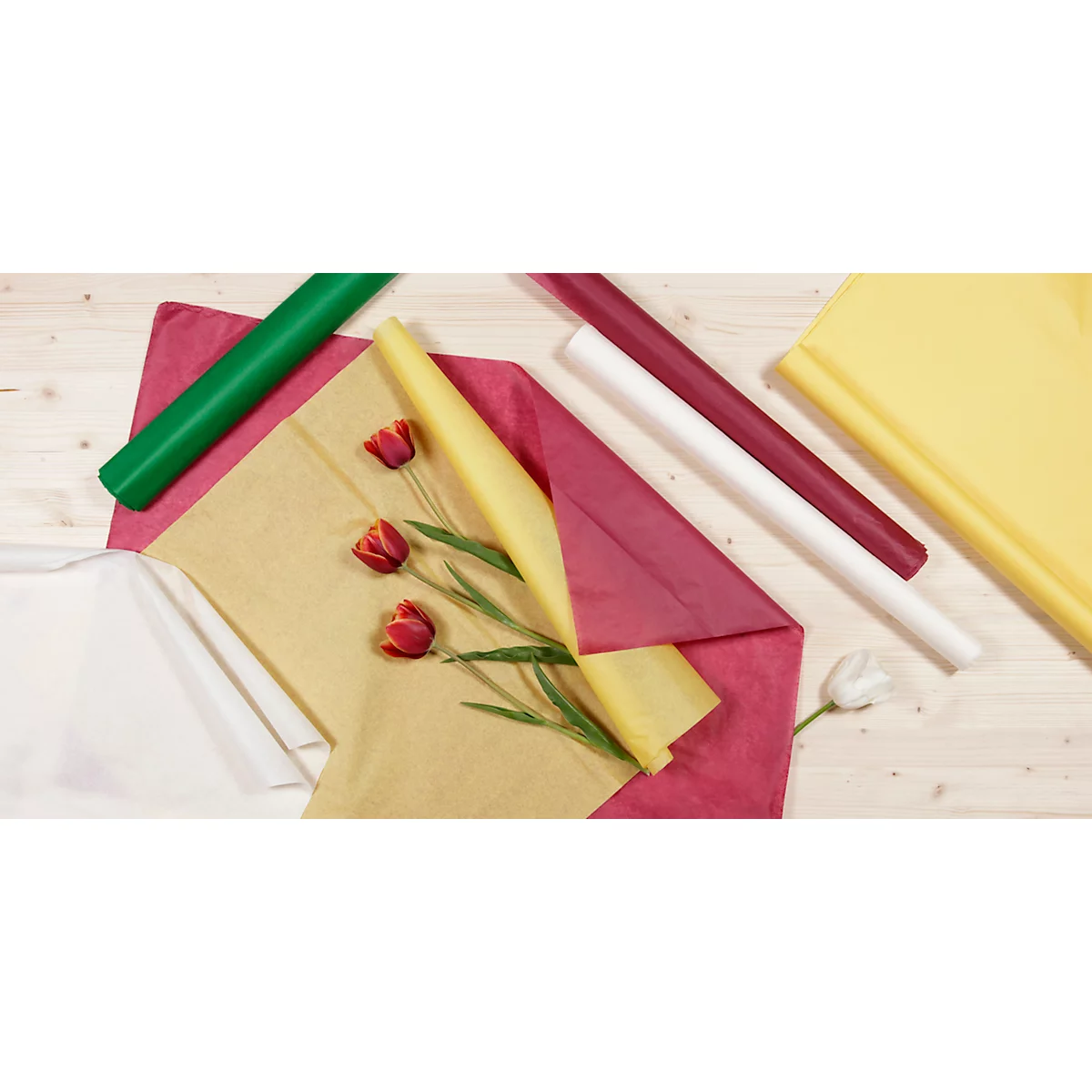 Arrangement de papiers cadeaux, tulipes et rouleaux. Rose, jaune, vert, marron et blanc. Sur fond de bois clair.