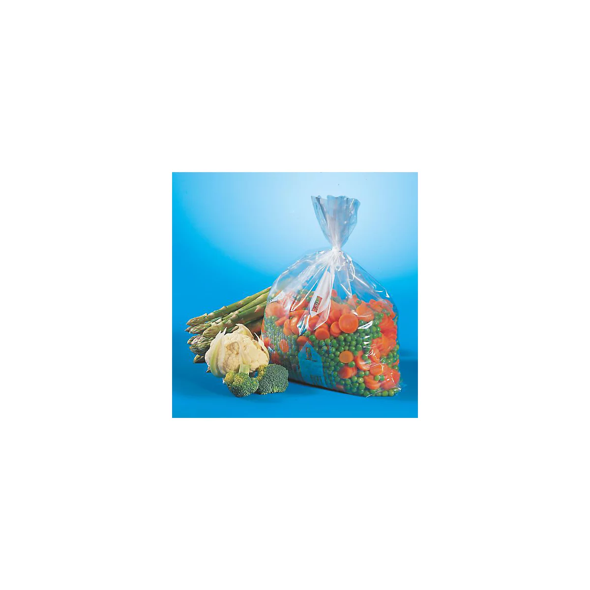 Eine Tüte mit geschnittenem Gemüse, Karotten, Erbsen und Spargel. Daneben Blumenkohl und Brokkoli, blauer Hintergrund.