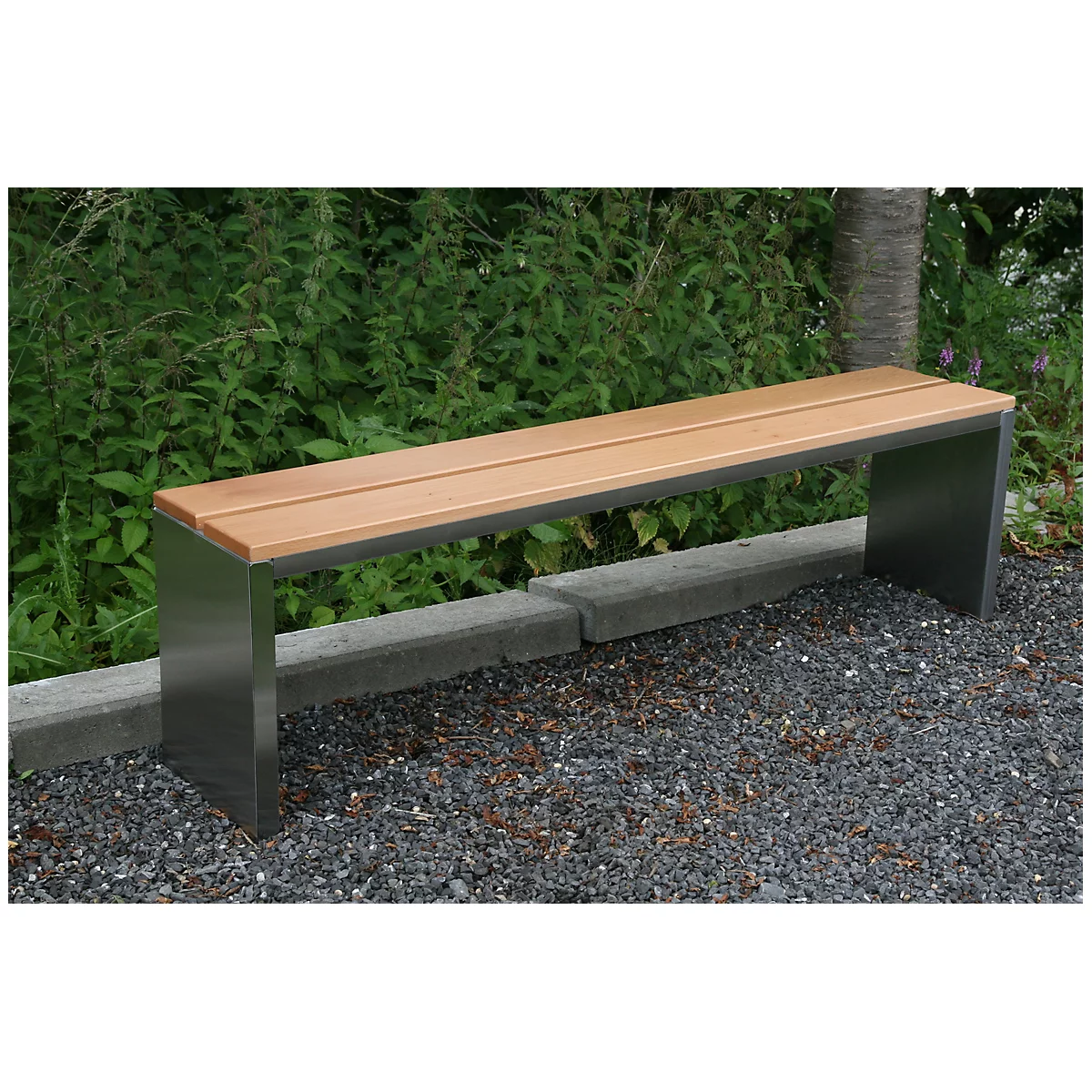 A modern park bench made of wood and metal in the garden. It stands on gravel, with bushes in the background.