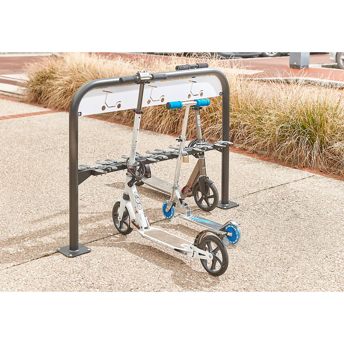 Two e-scooters in a rack. The left one is white with blue accents, the right one is brown.