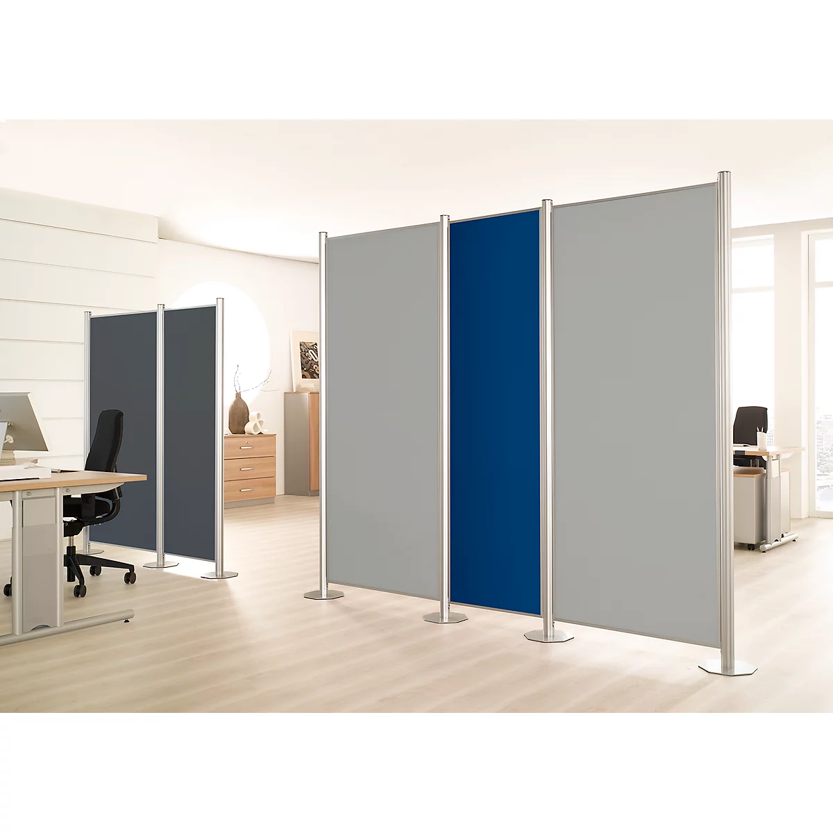 Office partition: Grey and blue fabric walls stand in an office. Bright environment with desk and chairs.