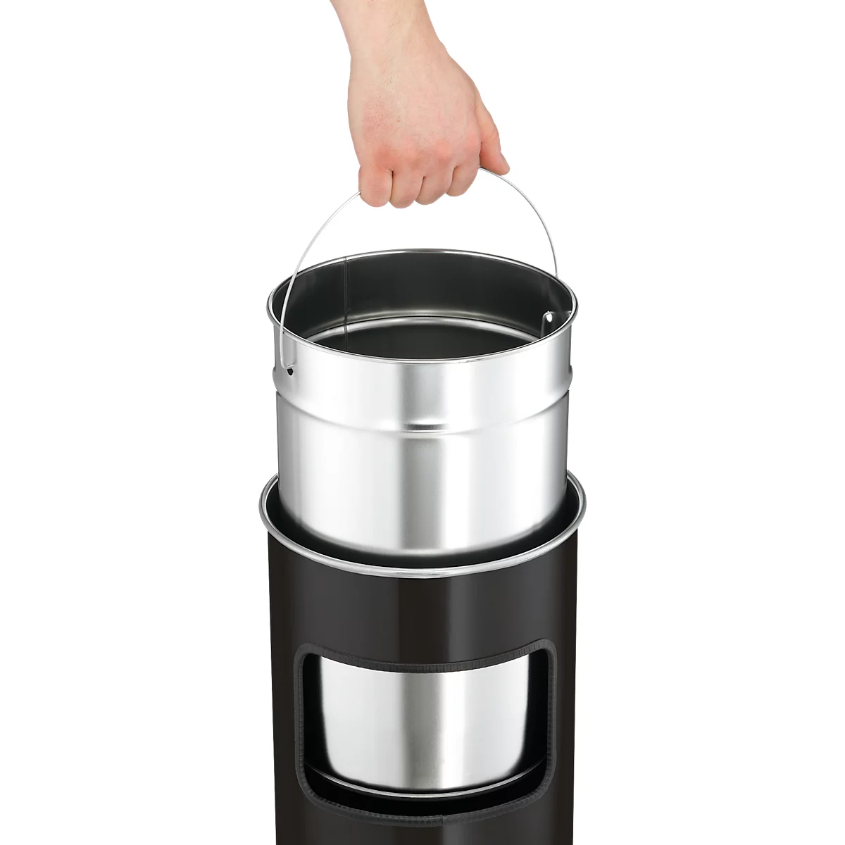 Hand holding a metal container with a handle, inserted into a black cylinder. There is also a metal container inside the cylinder.