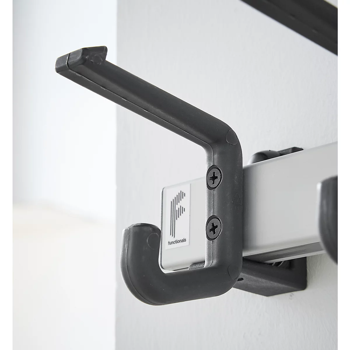 Primer plano de un gancho gris sujeto a un riel en la pared. El gancho tiene el logotipo "functionale".