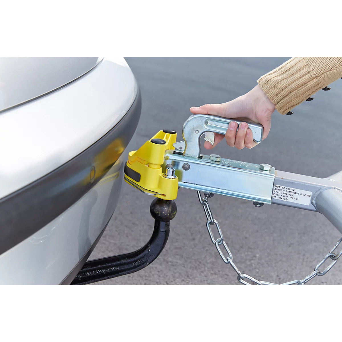 Close-up of a car with a trailer hitch. A hand is operating the trailer hitch system.
