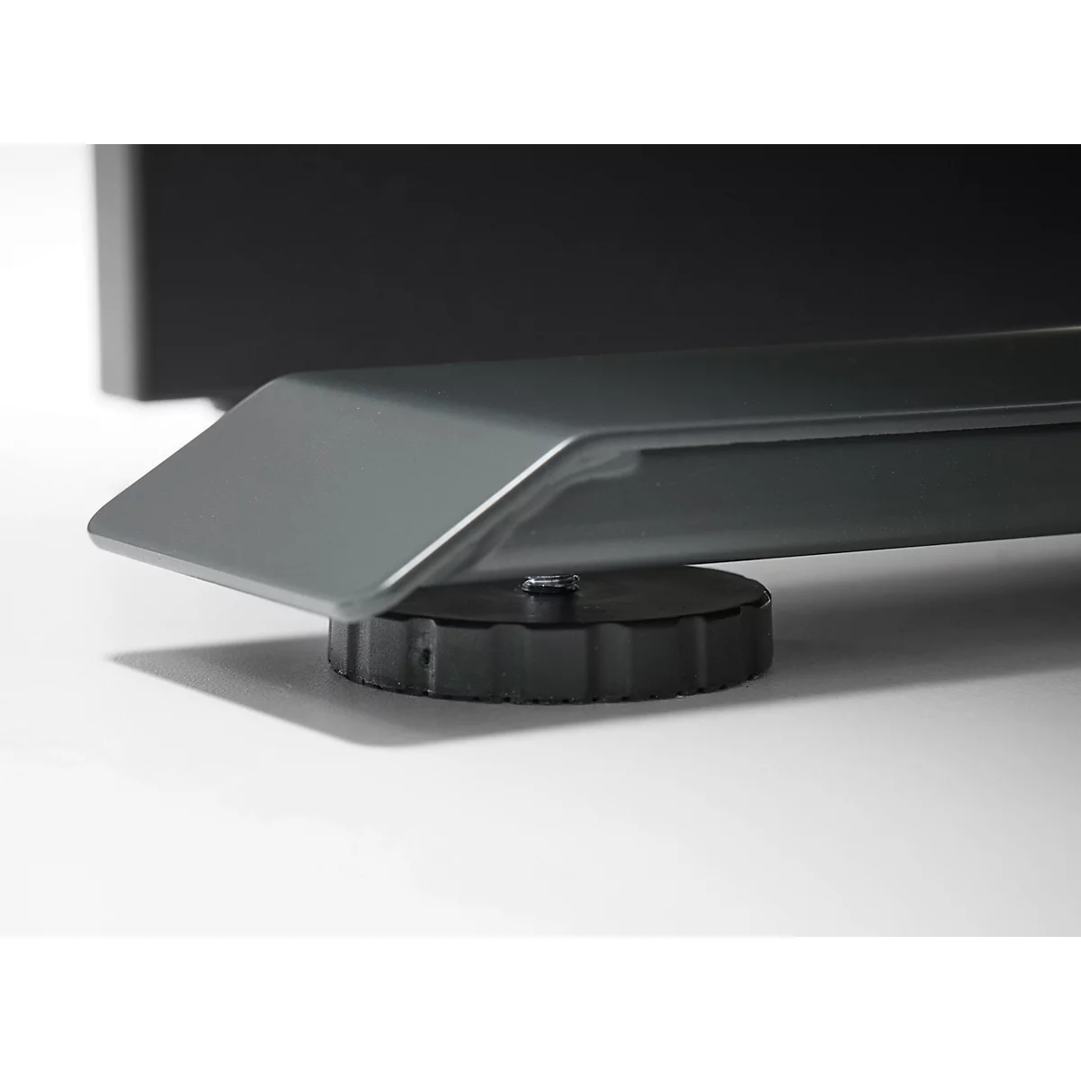 Gros plan du pied gris d'une table reposant sur un bouton rotatif noir et strié.