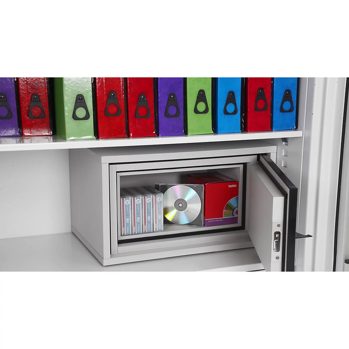 Ein grauer Tresor steht in einem Regal, gefüllt mit einer CD und Dokumentenhüllen.
